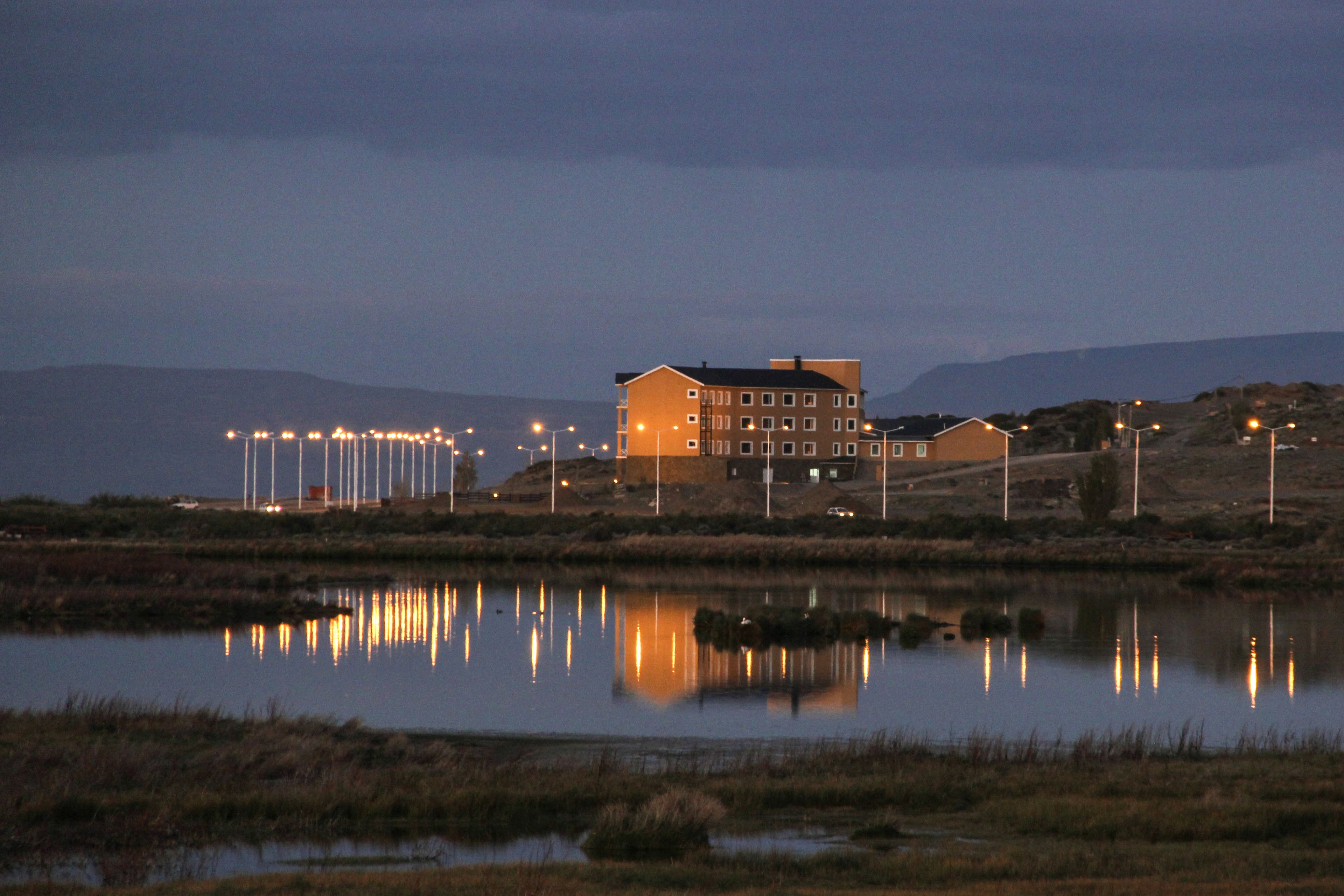 Un edificio reflejado en aguas tranquilas, rodeado de un paisaje natural.