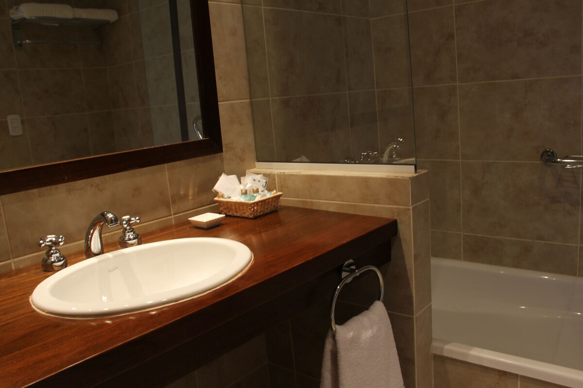 A bathroom with a sink, mirror, and bathtub.