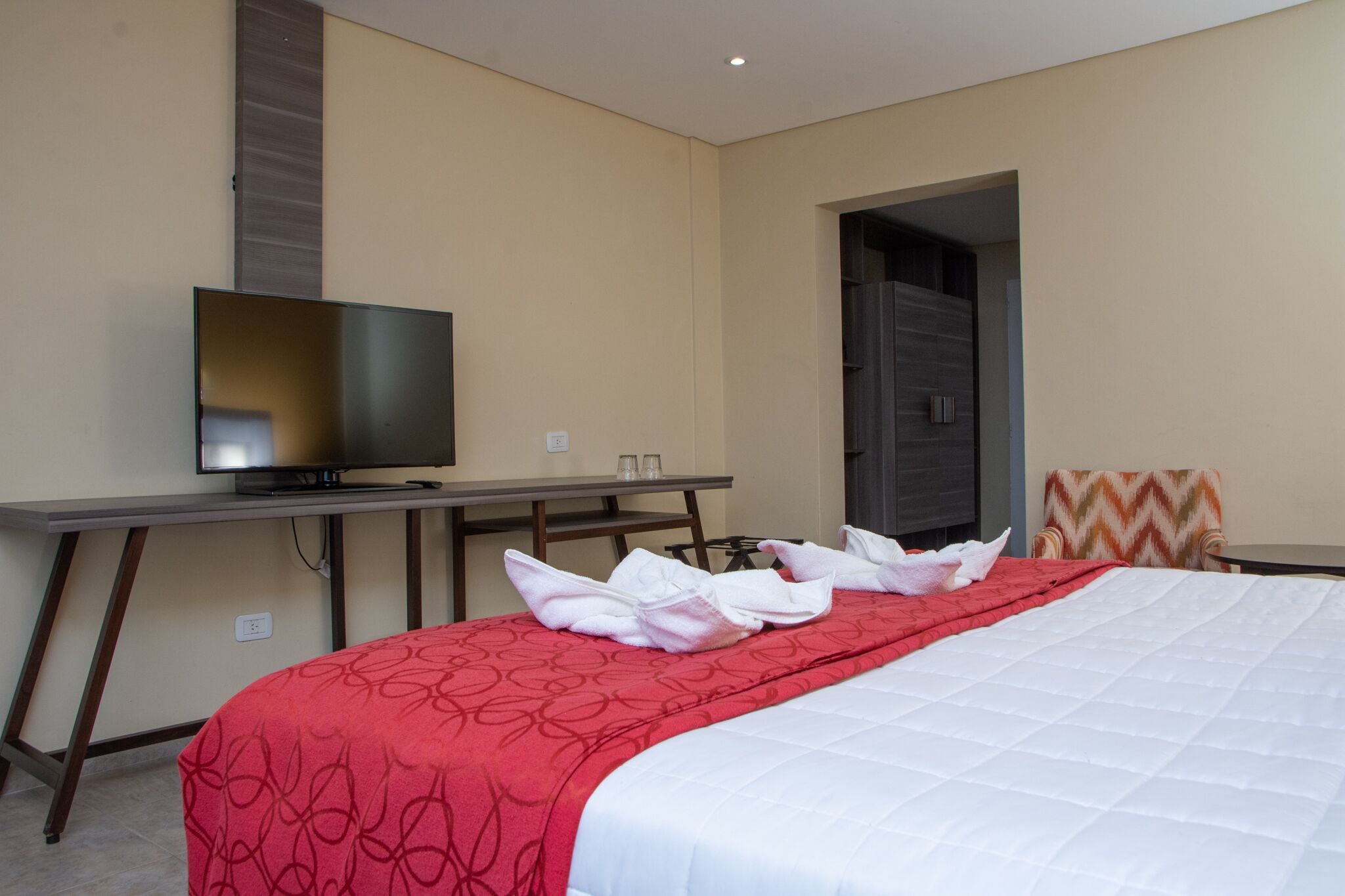 Una habitación de hotel con cama, televisión, escritorio y silla.