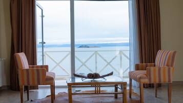 Una habitación con dos sillones a rayas, una mesa de centro de cristal con un centro de piñas y vistas a un cuerpo de agua a través de un amplio ventanal.