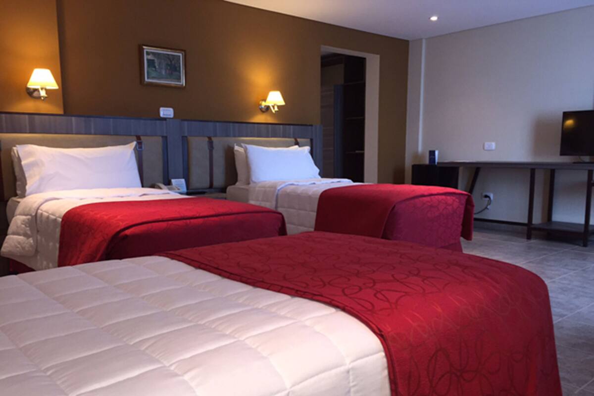 A hotel room with two beds, a desk, and a television.