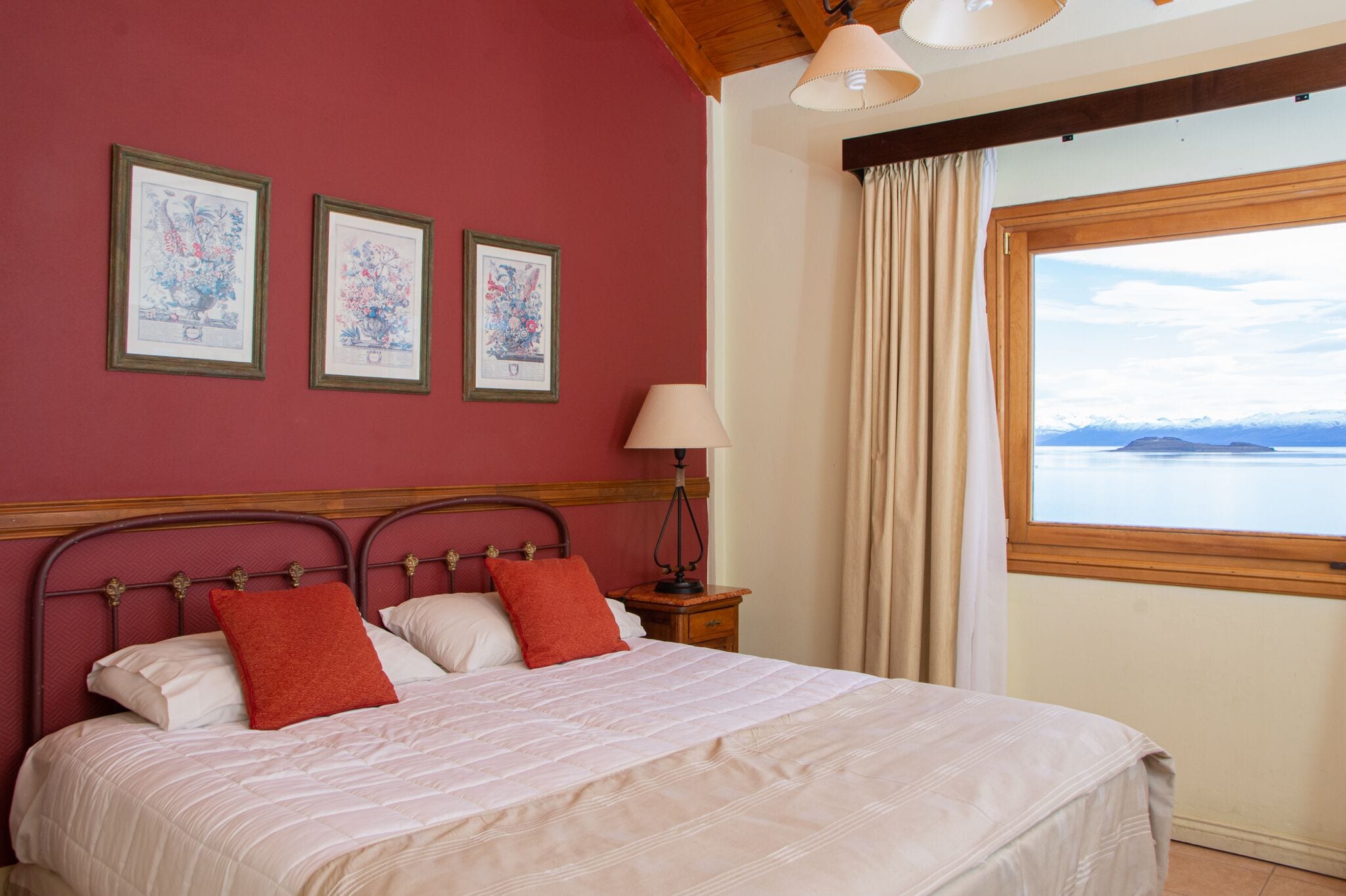 Ein Schlafzimmer mit Bett, Nachttisch, Lampe und Fenster mit Blick auf das Wasser.