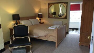 A bedroom with a wooden bed, two bedside lamps, a large mirror, a chair, and a wardrobe.