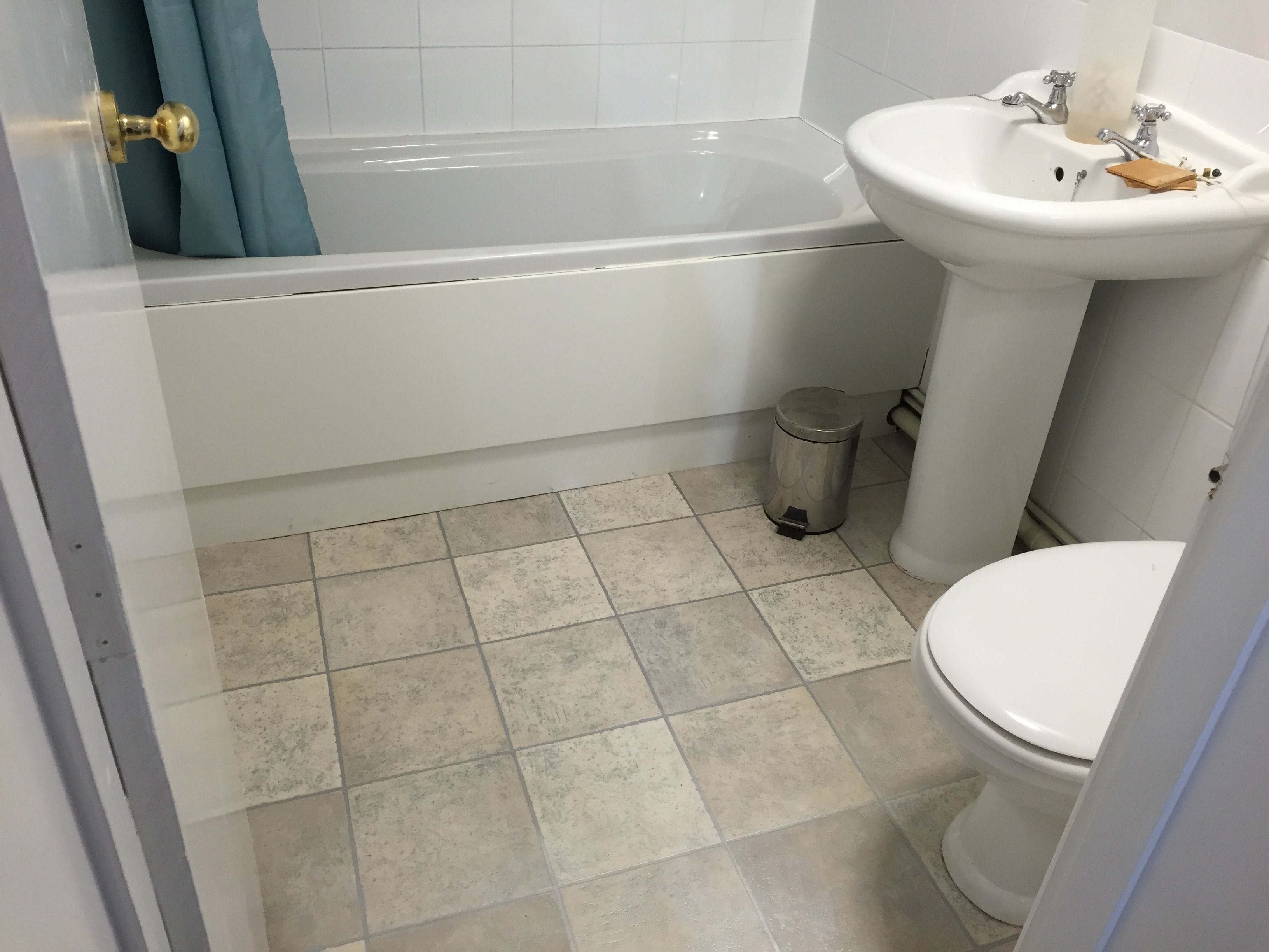 A bathroom with a bathtub, sink, toilet, and trash can.