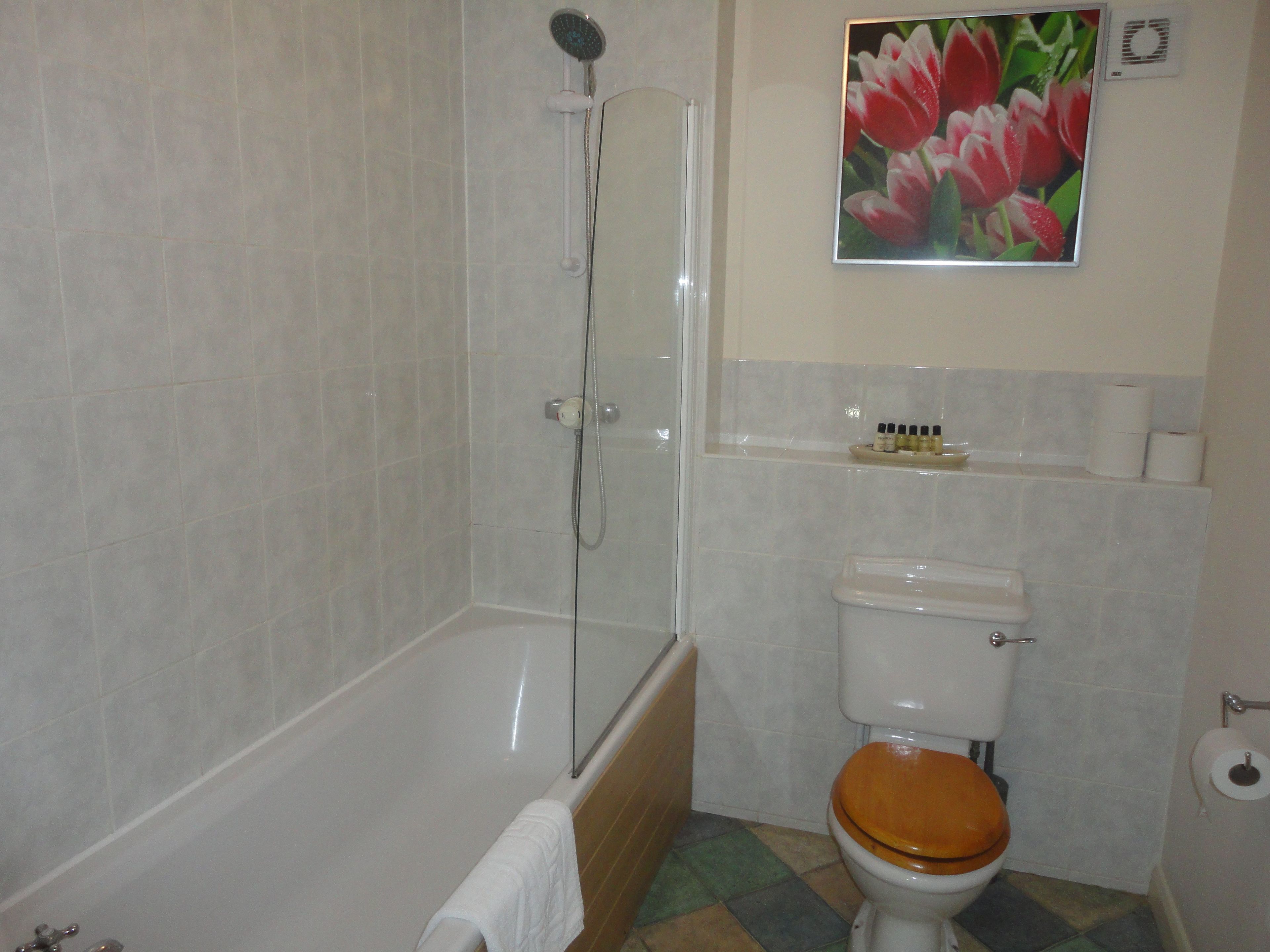 Et badeværelse med badekar, toilet og brusebad.