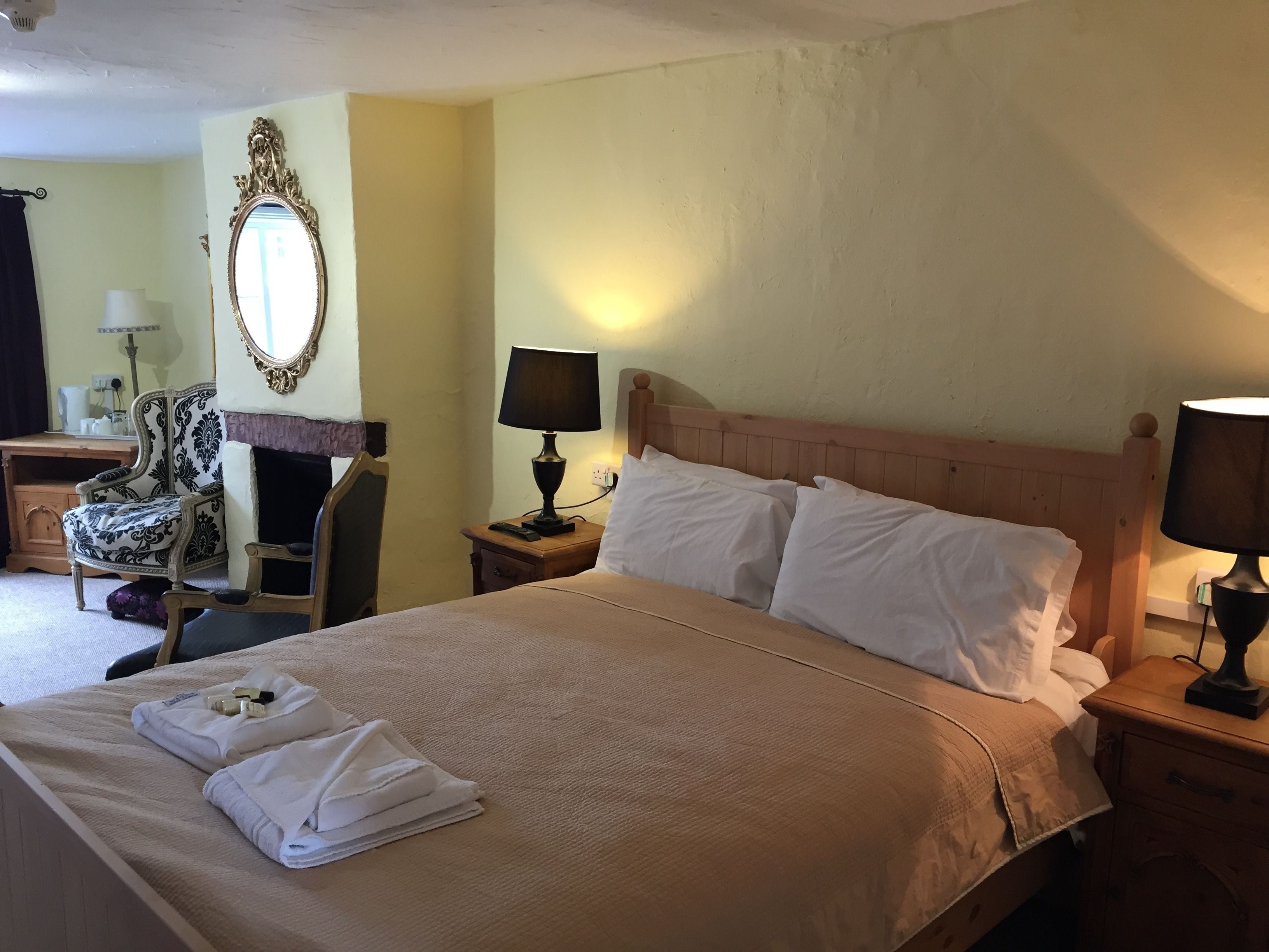 A hotel room with a large bed, two bedside tables, a chair, a desk, and a mirror.