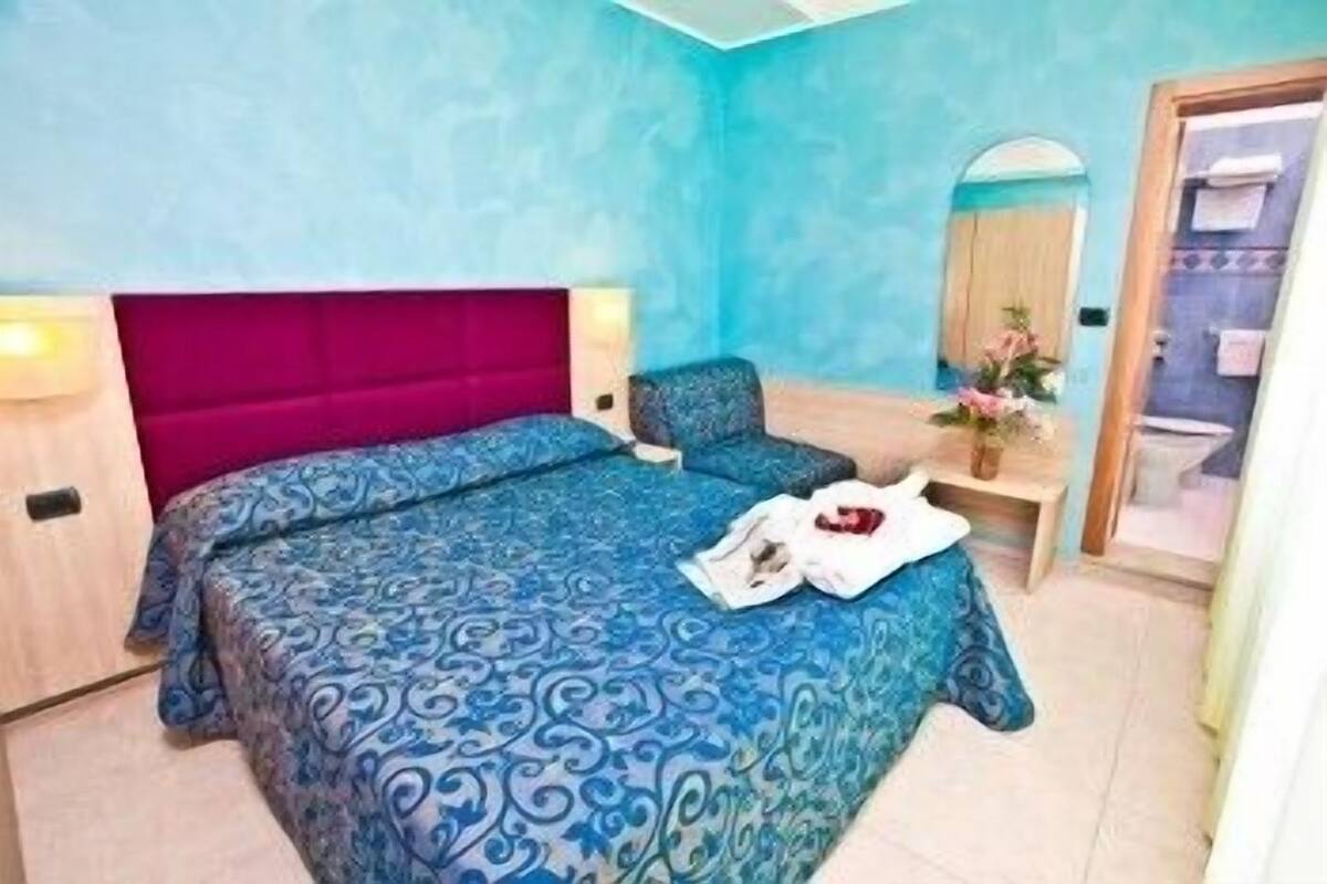 Un dormitorio con una cama grande, una silla, una mesita de noche y un espejo.