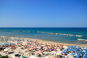 A beach with numerous umbrellas and people.