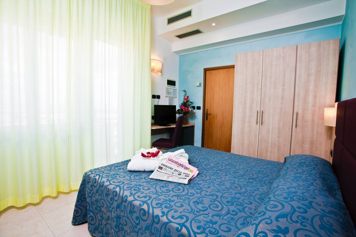 Una habitación de hotel con una cama, un escritorio y un armario.