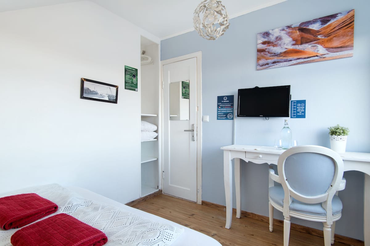Una habitación de hotel con cama, escritorio, silla, televisor y puerta.