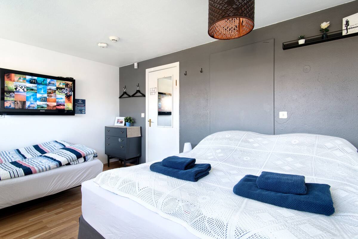 Un dormitorio con dos camas, un televisor en la pared y una puerta que da a otra habitación.