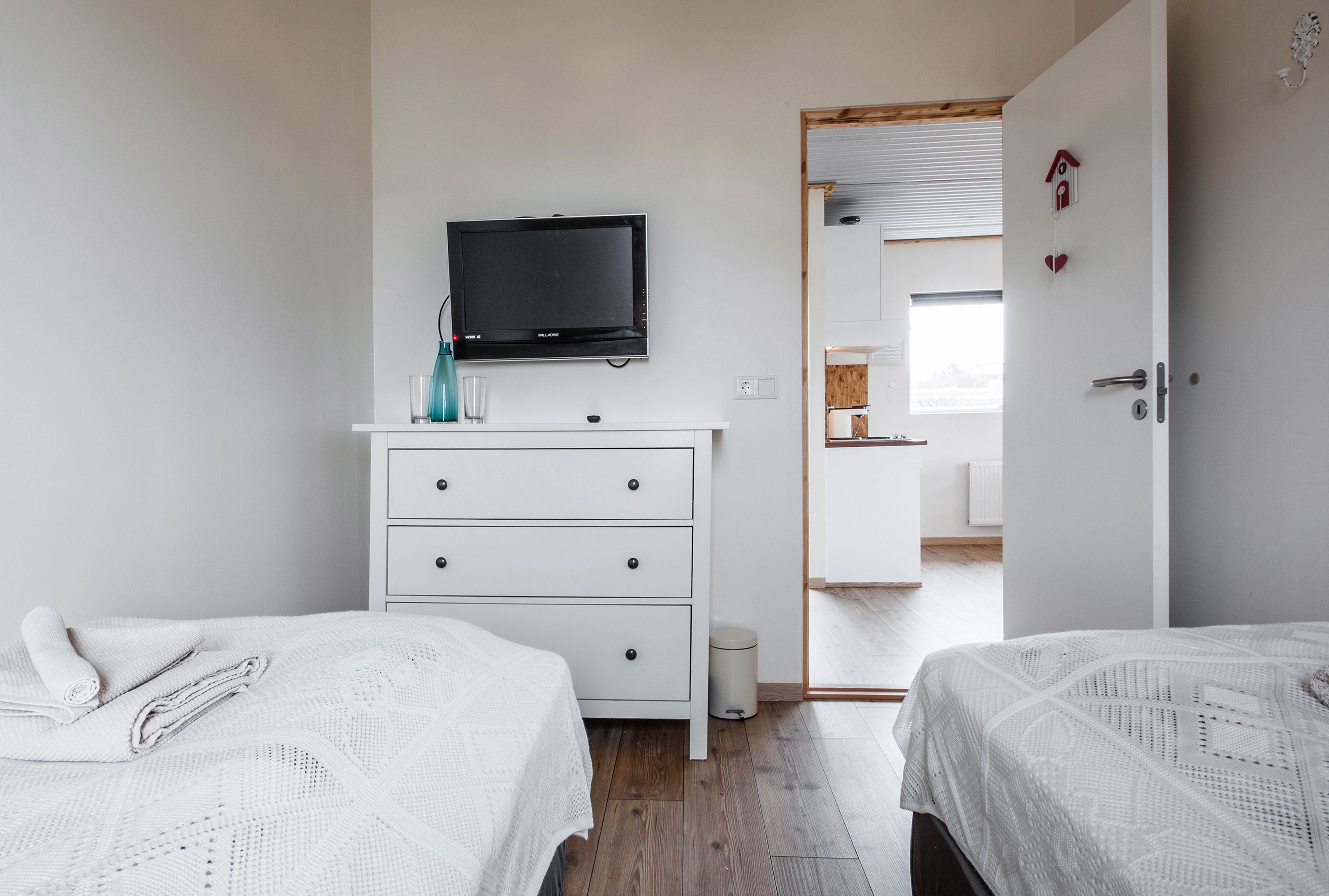 Un dormitorio con dos camas, un televisor, un aparador y una puerta que da a un baño.