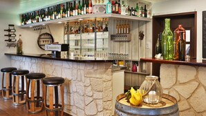 A bar area with stools, a stone wall, and shelves stocked with bottles and glasses. - Hotel Restaurant Ruppert (Walluf)
