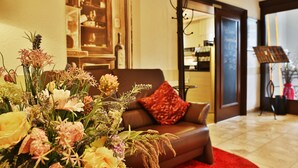 A living room with a brown sofa, a red cushion, and a floral arrangement. - Hotel Restaurant Ruppert (Walluf)