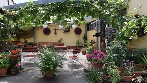 An outdoor seating area with tables and chairs, surrounded by potted plants and vines. - Hotel Restaurant Ruppert (Walluf)