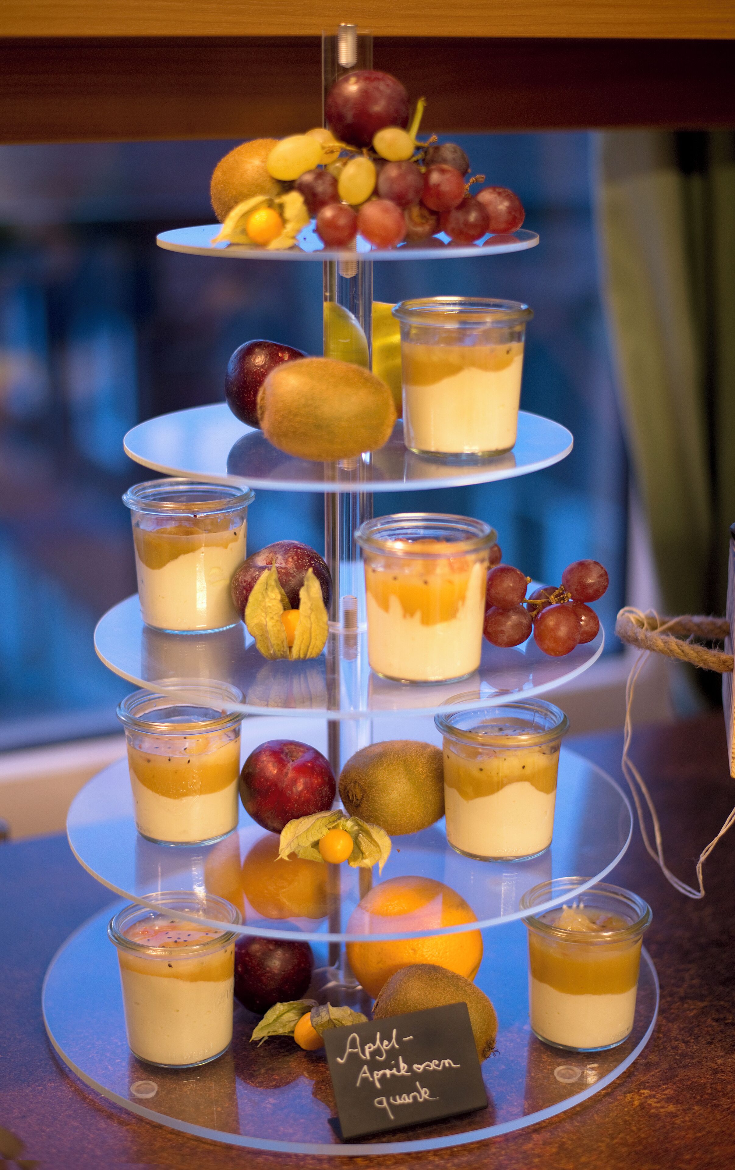Un expositor de postres de varios niveles con frutas y dulces.