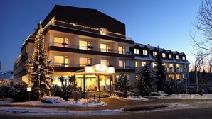 A multi-story hotel with a prominent entrance, balconies, and snow-covered surroundings.