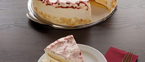A cake with a slice cut out, placed on a plate with a red napkin and fork beside it.