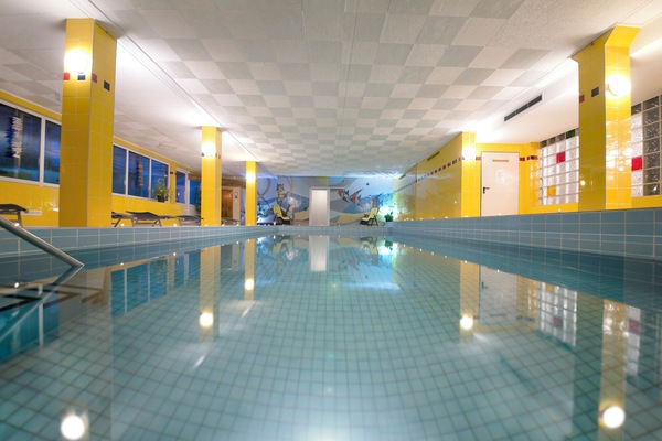 Una piscina techada, sombrillas, sillones reclinables de piscina