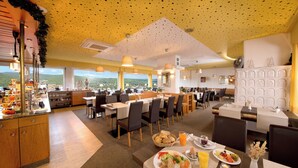 A restaurant with a high ceiling, large windows, and a buffet area.