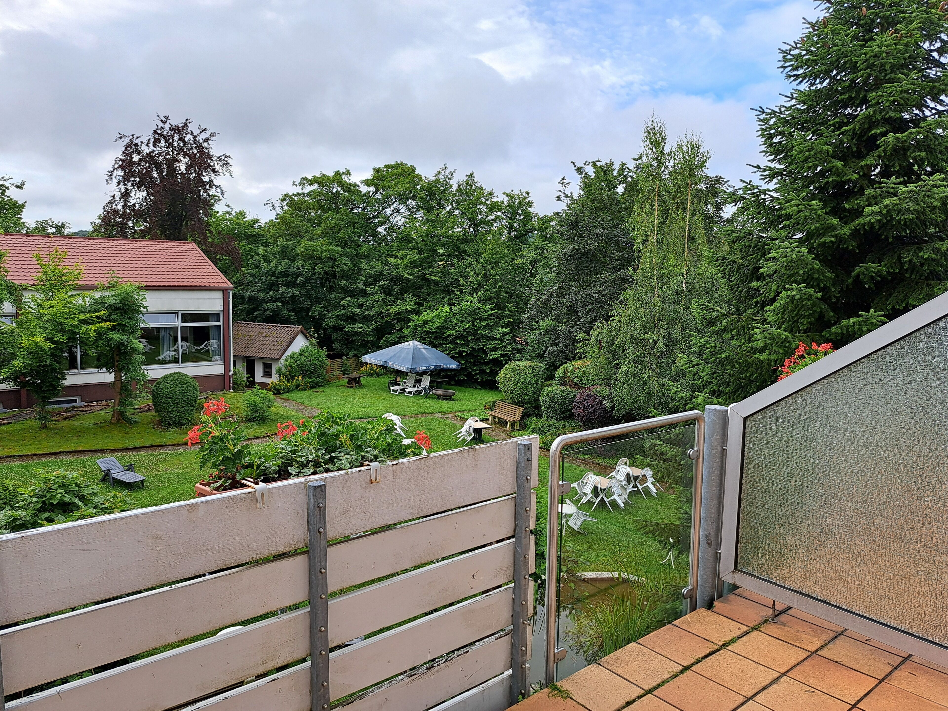 A garden with a bench, a small house, and a fence.