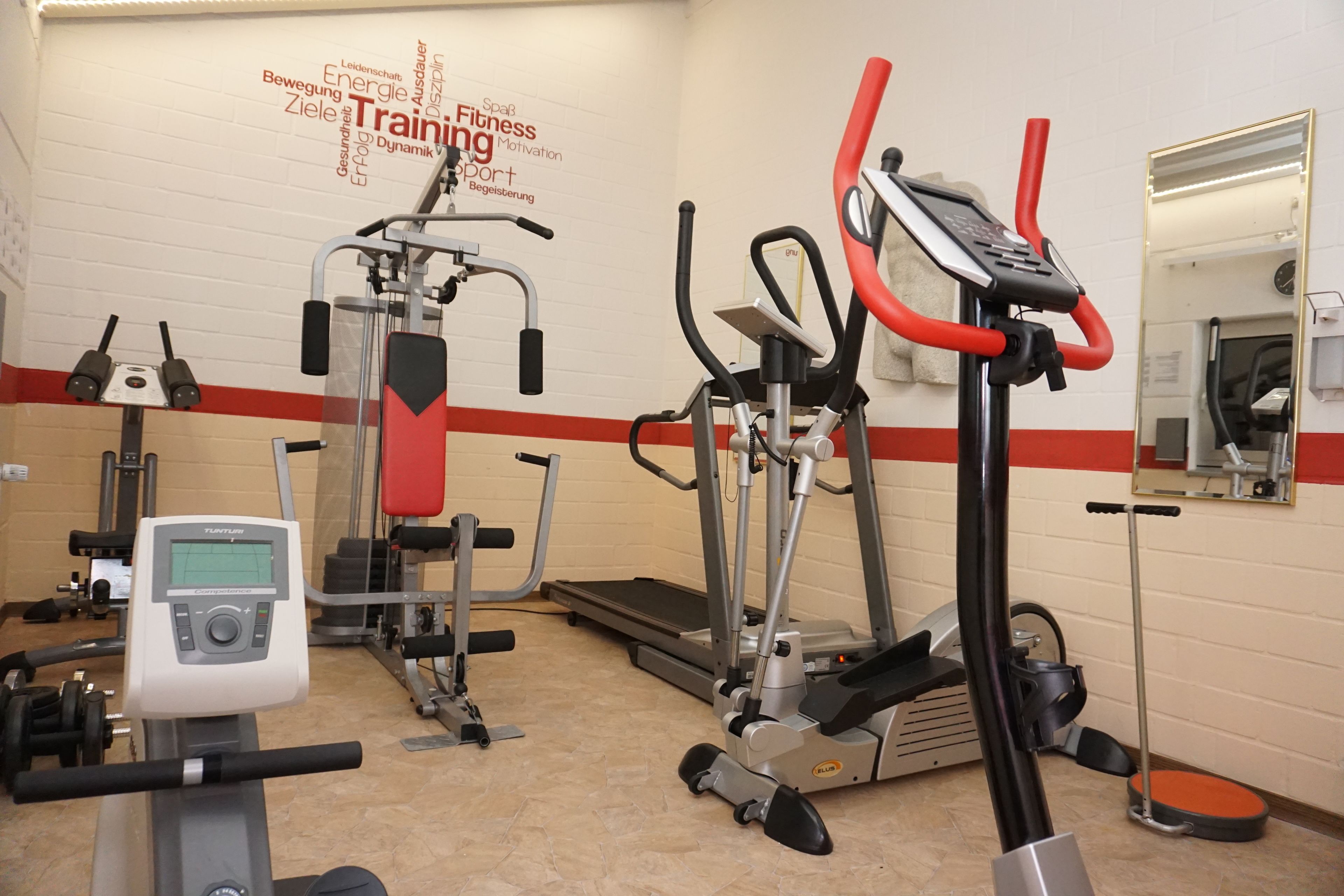 A gym with cardio machines, weight machines, and a mirror.
