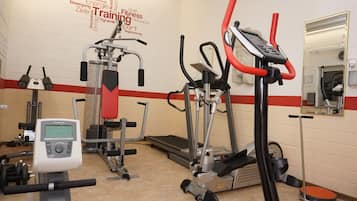 Et fitnesscenter med løbebånd, styrkemaskiner og et spejl.