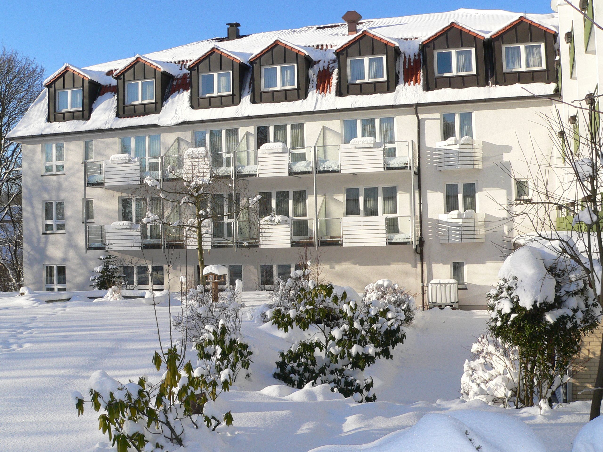 A multi-story hotel with balconies, snow-covered surroundings, and a clear sky.