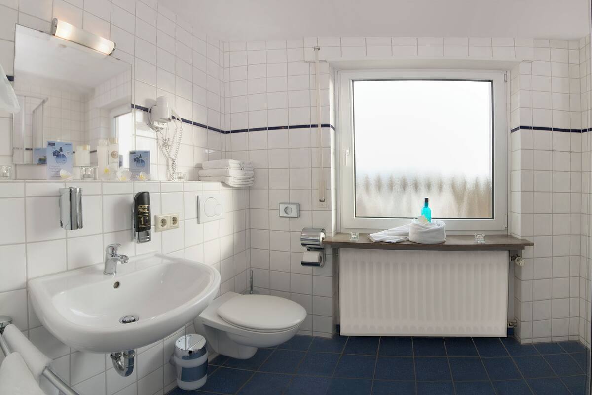 Un baño con lavamanos, inodoro y ventana con vistas.