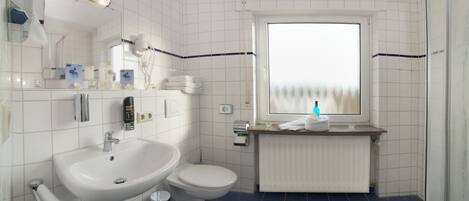 A bathroom with a white sink, toilet, and a window with a view.