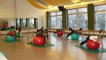 A spacious room with large windows, green mats, and red exercise balls.