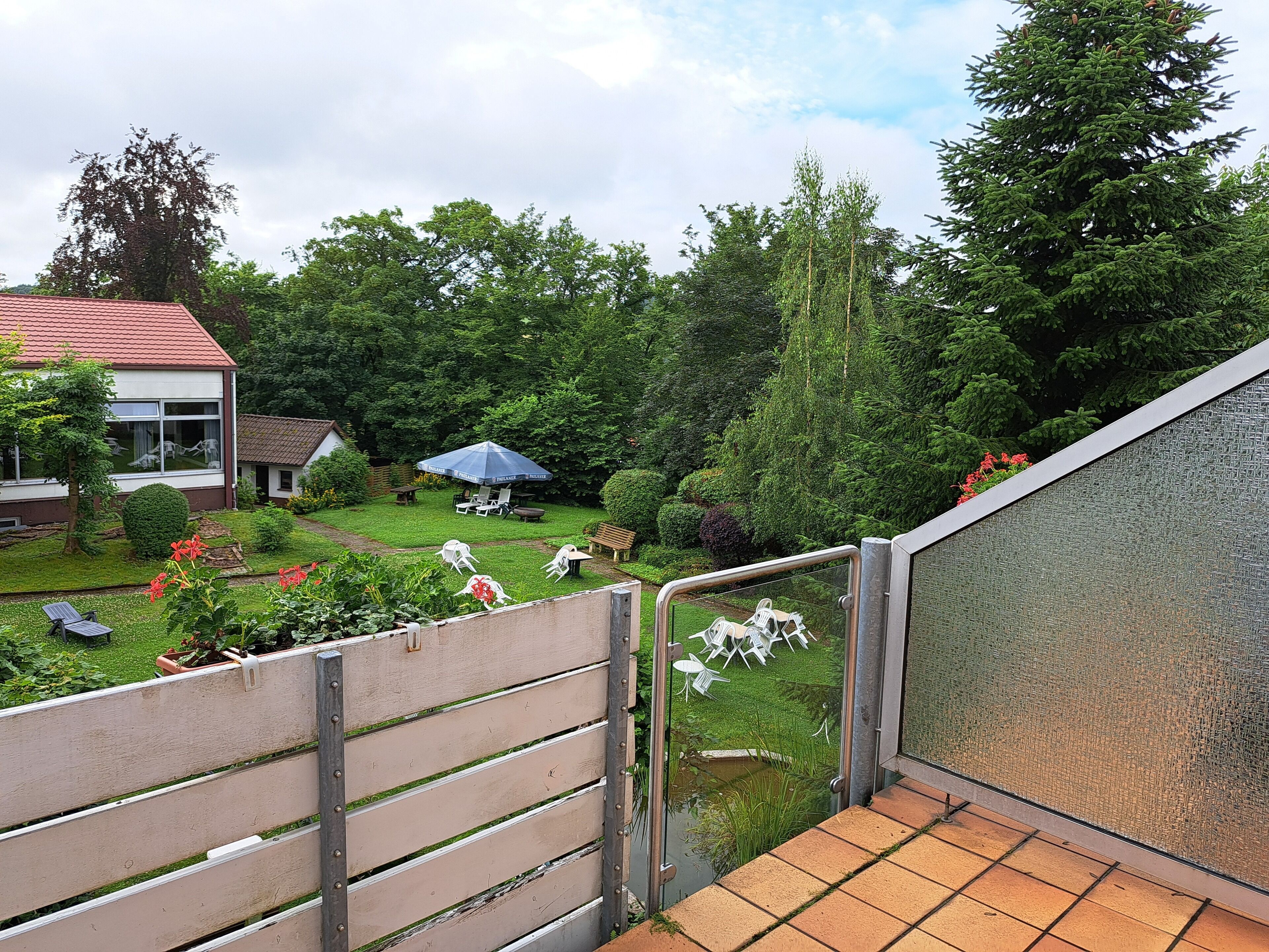 A residential backyard with a patio, a small pond, and various plants.