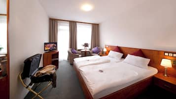 Habitación de hotel con dos camas, un escritorio con computadora, una silla y un televisor.