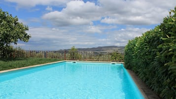 Een buitenzwembad, parasols bij het zwembad en ligstoelen