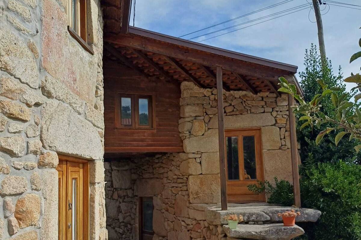 A stone building with a wooden door and windows, a stone staircase, and potted plants.