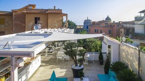 An outdoor patio with white furniture, a large umbrella, and potted plants. - Magi House Relais (Sorrento)