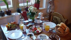 A breakfast table set with plates, cups, and various food items. - Gaestehaus Loschwitz (Dresden)