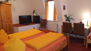 A room with a bed, a desk with a computer and speakers, a chair, and a window with curtains. - Gaestehaus Loschwitz (Dresden)