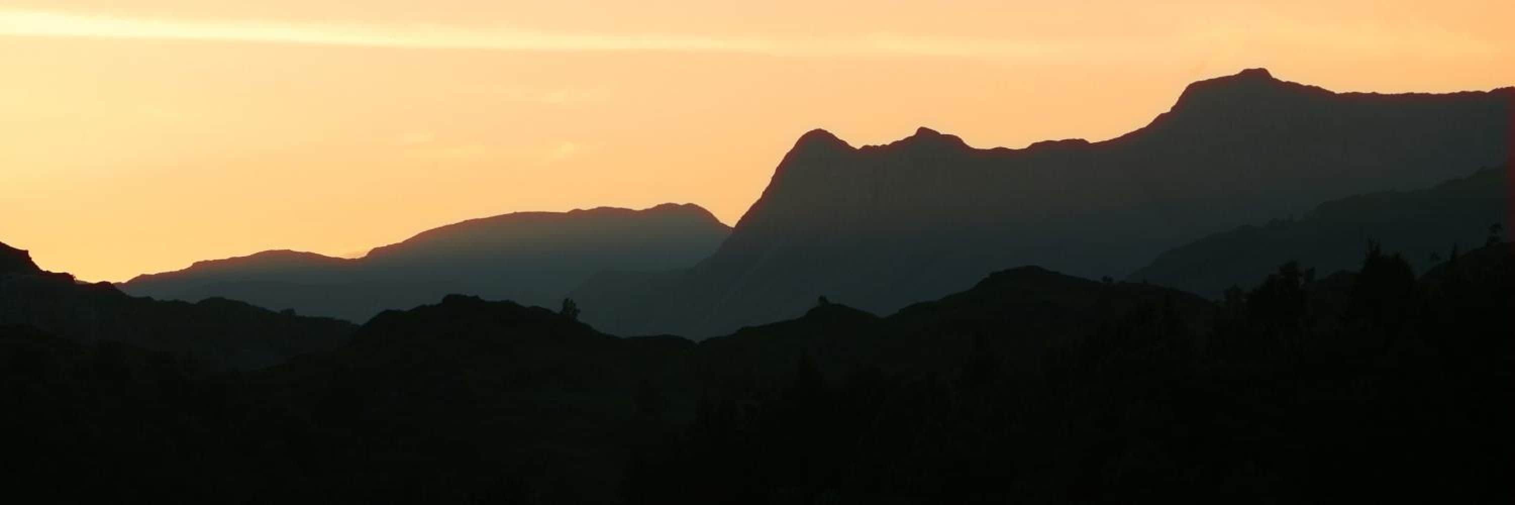 Silueta de una cadena montañosa contra un cielo al atardecer.
