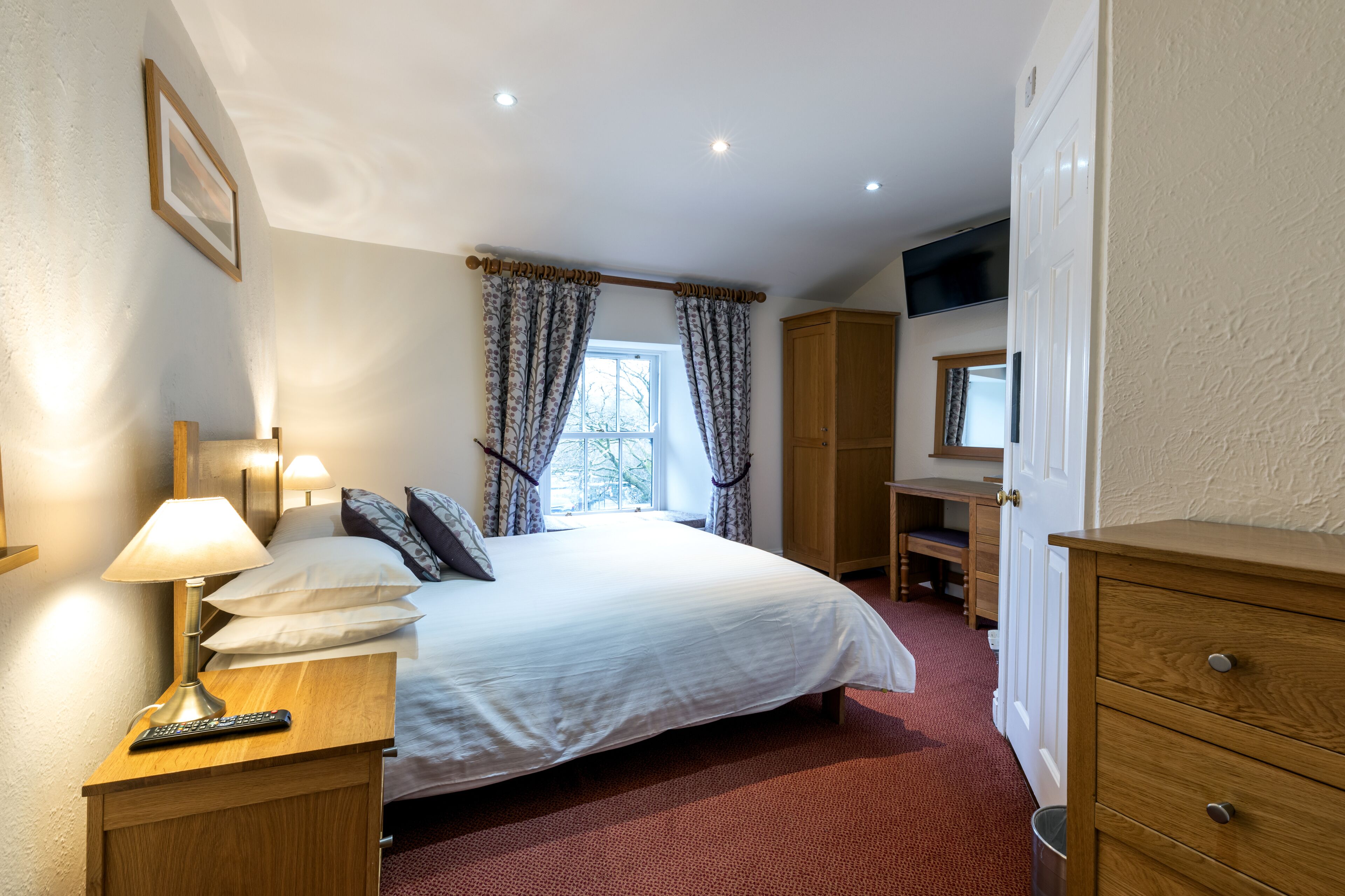 A neatly arranged bedroom with a bed, bedside lamp, and a desk with a chair.