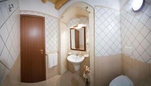 A bathroom with a wooden door, a sink, a mirror, and a toilet.