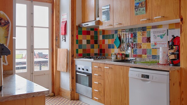 Una cocina con armarios de madera, un salpicadero colorido, un lavavajillas Bosch y una estufa a gas.