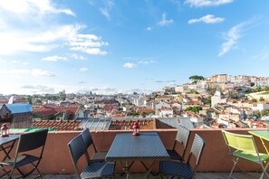Una terraza en la azotea con mesa y sillas, con vistas a una ciudad histórica de gran densidad de edificios.