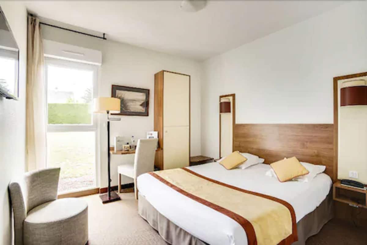 Une chambre d’hôtel avec un grand lit, un bureau, une chaise et une armoire.