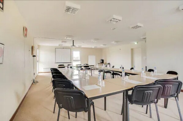 Une salle de conférence avec une longue table, des chaises et un tableau blanc.