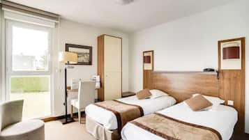 Una habitación de hotel con dos camas, un escritorio, una silla y un ventanal grande.