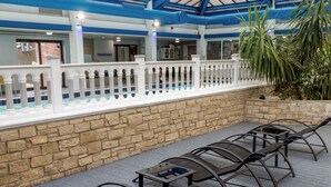 An indoor patio area with a stone wall, a white fence, and a row of metal chairs. - Best Western Weymouth Hotel Rembrandt (Weymouth)