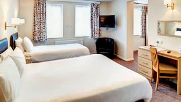 A hotel room with two beds, a desk, a chair, a television, and a window with curtains.