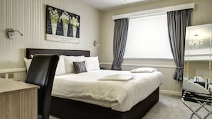 A neatly made bed with white linens, a black headboard, and a bedside table with a lamp. - Best Western Weymouth Hotel Rembrandt (Weymouth)