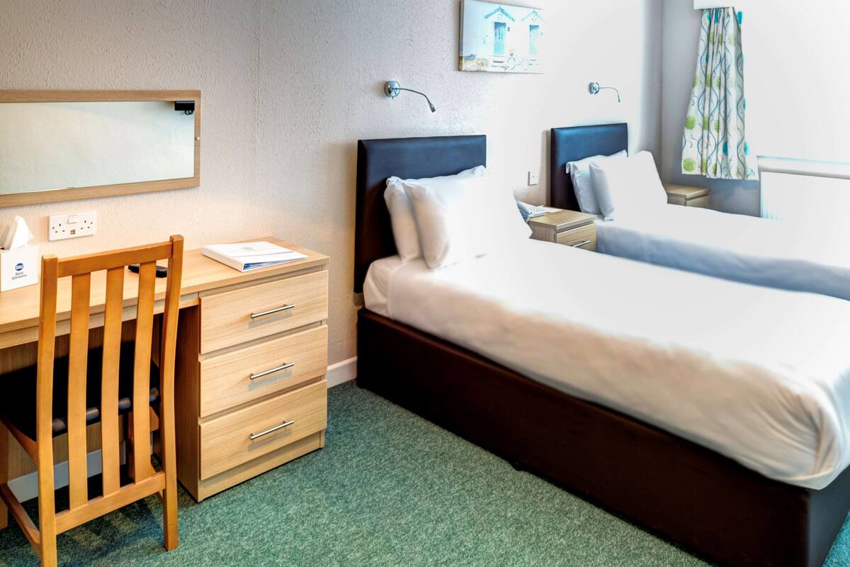 A hotel room with a bed, a desk, a chair, and a small table.